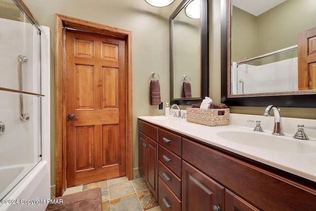 bathroom featuring stone finish floor, a sink, and double vanity