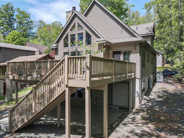 24 Glen Rd, Lake Ariel, PA 18436 - back of property with a chimney, a wooden deck, roof with shingles, and stairs