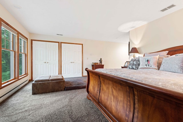 carpeted bedroom featuring visible vents, baseboard heating, and multiple closets