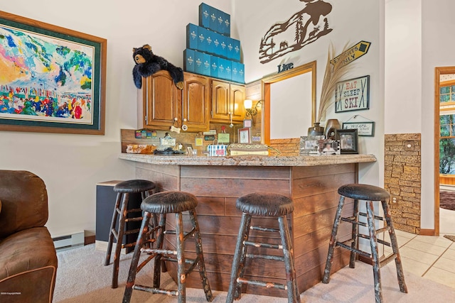 bar with a bar, light tile patterned floors, a baseboard radiator, and baseboards