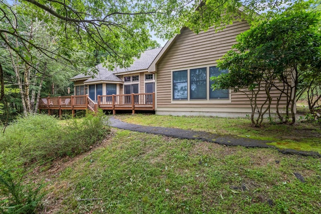 back of house featuring roof with shingles and a wooden deck