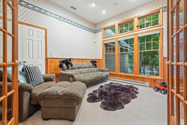 living area featuring a baseboard radiator, a wainscoted wall, carpet floors, visible vents, and wallpapered walls