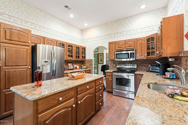 kitchen featuring a kitchen island, a sink, visible vents, appliances with stainless steel finishes, and wallpapered walls