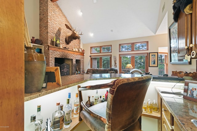 kitchen featuring a brick fireplace, visible vents, and high vaulted ceiling