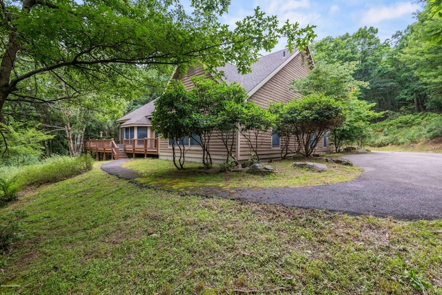 view of yard featuring a deck and aphalt driveway