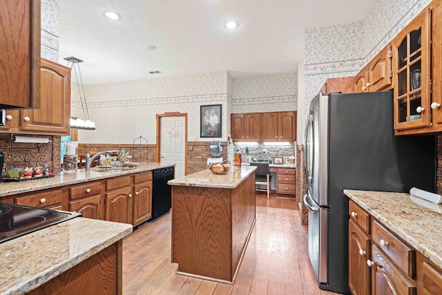 kitchen with black dishwasher, brown cabinetry, a sink, and wallpapered walls