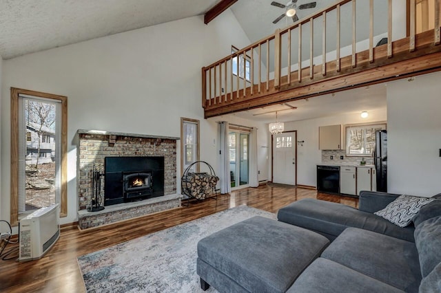 living area with a brick fireplace, ceiling fan, beam ceiling, wood finished floors, and high vaulted ceiling