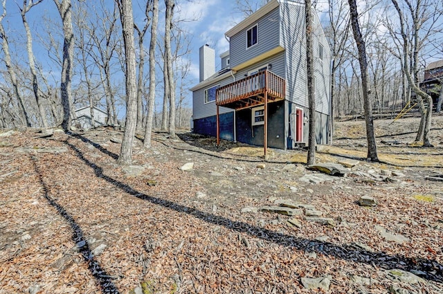 rear view of property featuring a wooden deck and a chimney