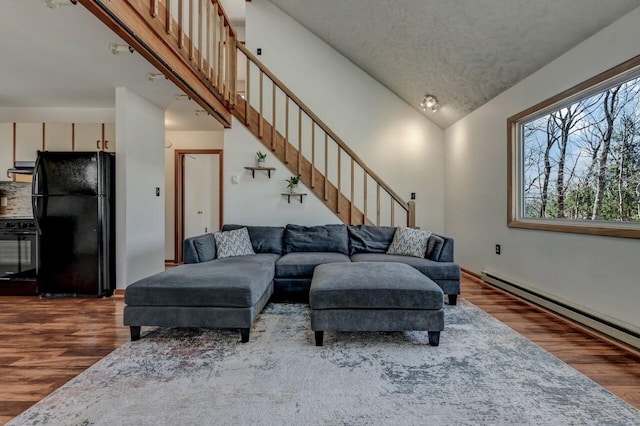 living room featuring stairway, high vaulted ceiling, wood finished floors, and a baseboard radiator