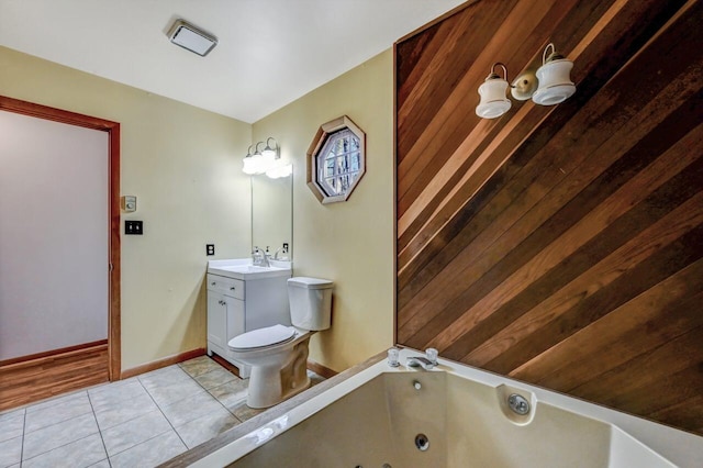 bathroom featuring tile patterned flooring, baseboards, toilet, a tub with jets, and vanity