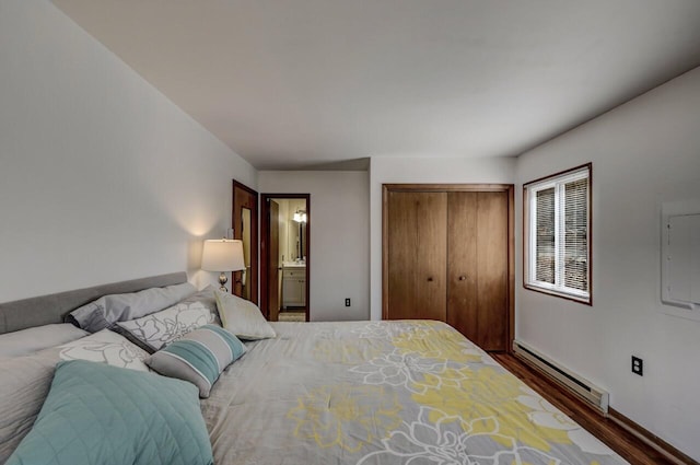 bedroom featuring a baseboard heating unit, ensuite bath, wood finished floors, and a closet