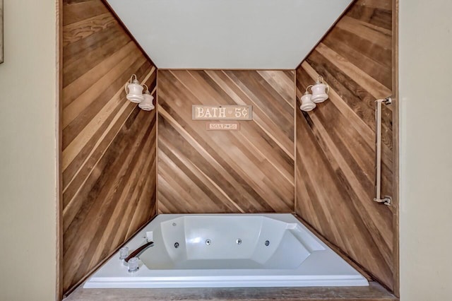 interior space with a jetted tub and wood walls