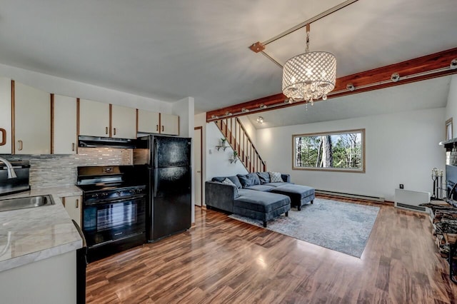 kitchen with beam ceiling, black appliances, light countertops, under cabinet range hood, and a baseboard heating unit