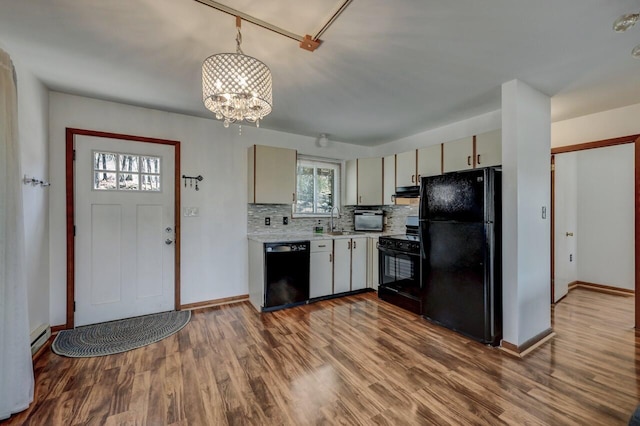 kitchen featuring baseboards, light countertops, decorative backsplash, dark wood-style floors, and black appliances