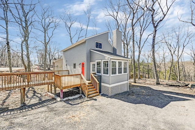 view of front facade with a deck, gravel driveway, and a chimney