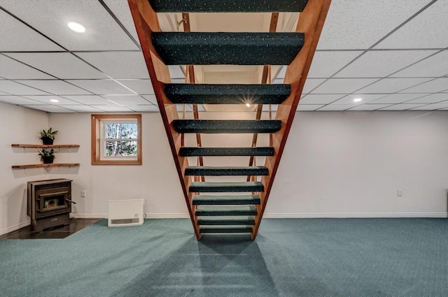 basement featuring baseboards, carpet floors, and a wood stove