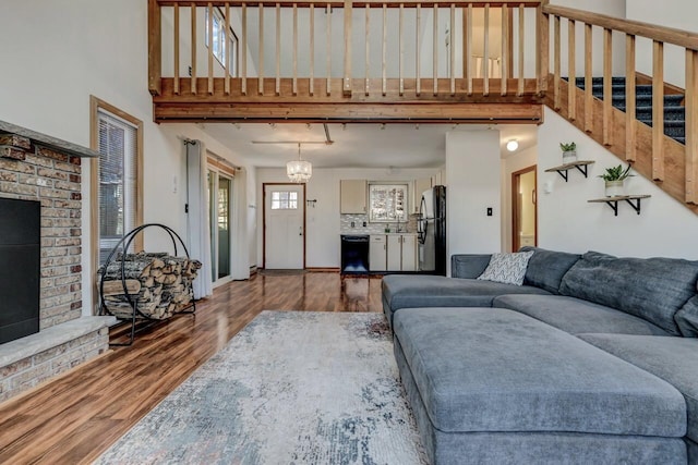 living room with wood finished floors, stairway, a high ceiling, a fireplace, and baseboards