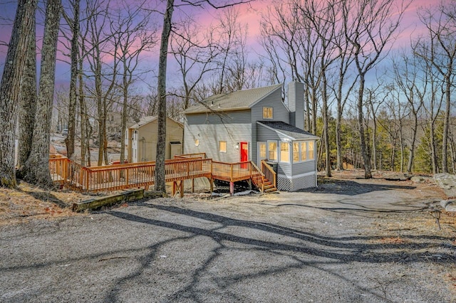 view of front of house featuring a deck, driveway, and a chimney