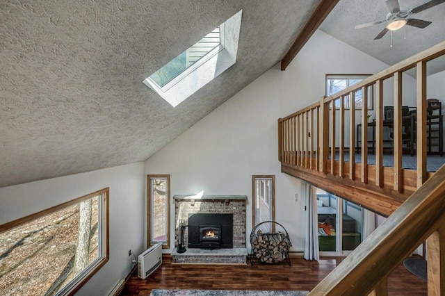 living area with wood finished floors, a skylight, ceiling fan, a textured ceiling, and beamed ceiling