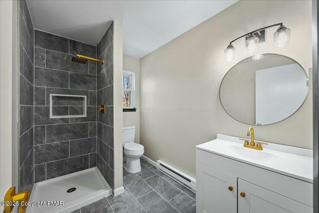 bathroom featuring a baseboard heating unit, tiled shower, vanity, and toilet