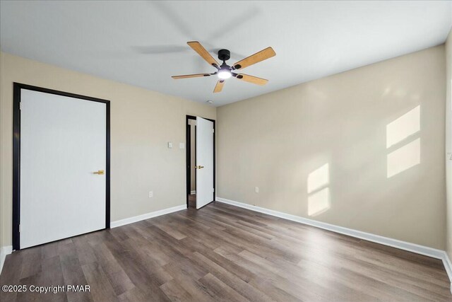 unfurnished bedroom with ceiling fan, baseboards, and wood finished floors