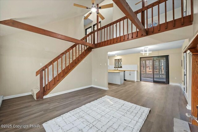 unfurnished living room featuring stairway, dark wood-style flooring, and baseboards