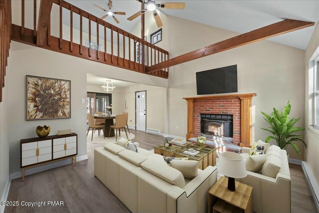 living room with baseboard heating, ceiling fan, wood finished floors, high vaulted ceiling, and baseboards