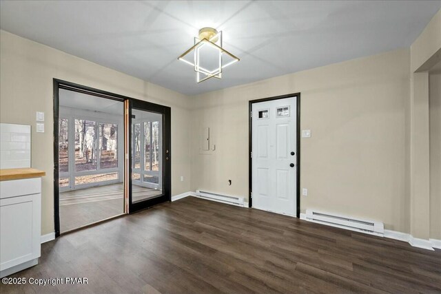 spare room with baseboards, a baseboard heating unit, and dark wood finished floors