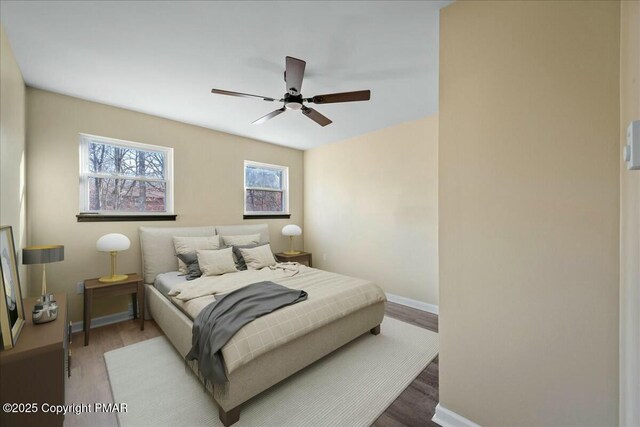 bedroom featuring ceiling fan, baseboards, and wood finished floors