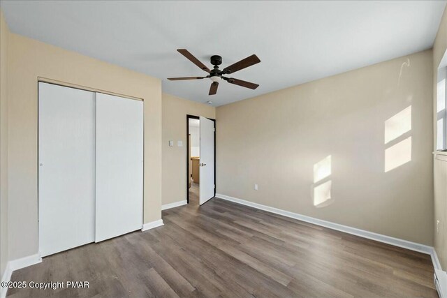 unfurnished bedroom featuring a closet, wood finished floors, a ceiling fan, and baseboards