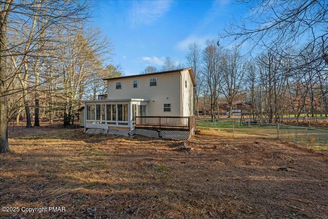 rear view of property with a sunroom, fence, and a wooden deck