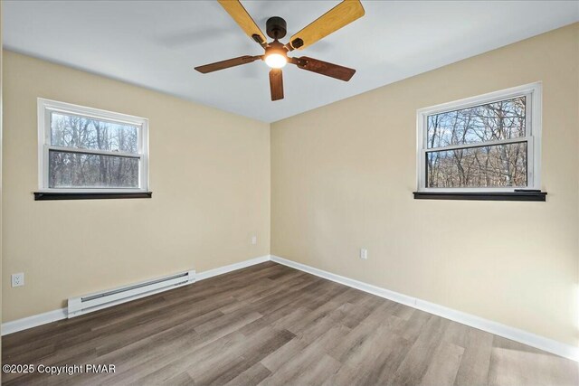 unfurnished room with a baseboard heating unit, ceiling fan, baseboards, and wood finished floors