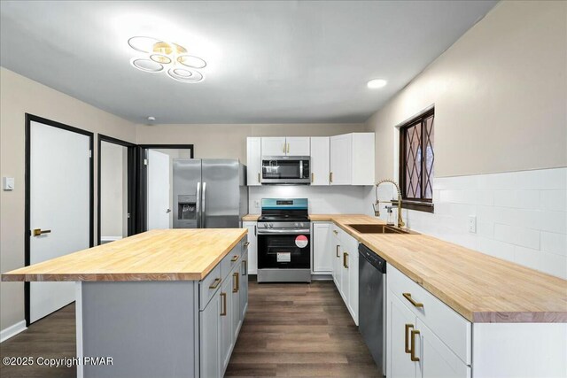 kitchen featuring wooden counters, appliances with stainless steel finishes, a sink, and white cabinets