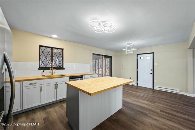 kitchen featuring butcher block counters, appliances with stainless steel finishes, a baseboard heating unit, dark wood-type flooring, and a sink