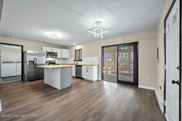 kitchen featuring a center island, stainless steel appliances, wooden counters, white cabinetry, and separate washer and dryer