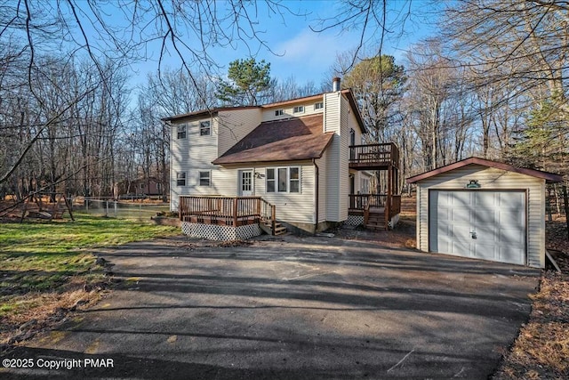 exterior space with a wooden deck, a garage, and an outbuilding