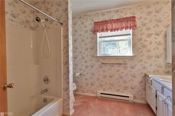 full bath with shower / washtub combination, a baseboard radiator, vanity, and wallpapered walls