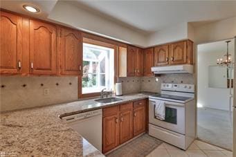 kitchen with under cabinet range hood, white appliances, a sink, brown cabinets, and tasteful backsplash