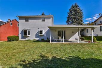 back of property with a lawn and a patio