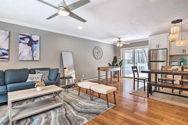 living room with hardwood / wood-style floors, a ceiling fan, baseboards, ornamental molding, and a baseboard heating unit