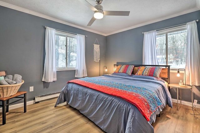 bedroom featuring a baseboard heating unit, multiple windows, wood finished floors, and ornamental molding