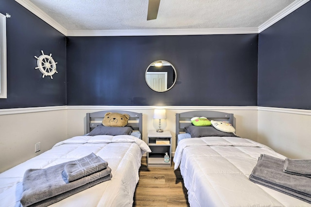 bedroom with crown molding, wood finished floors, and a textured ceiling