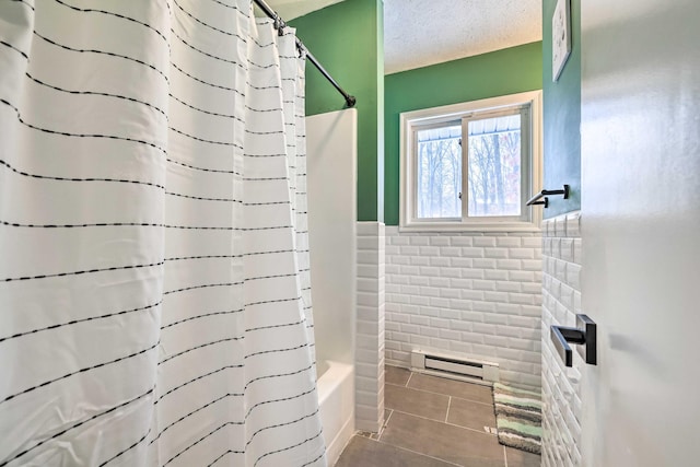 bathroom with tile patterned floors, shower / bathtub combination with curtain, a textured ceiling, tile walls, and wainscoting