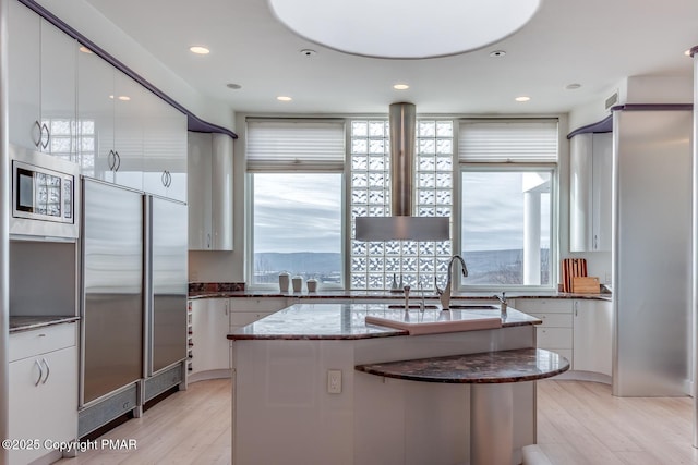 kitchen with built in appliances, a wealth of natural light, a sink, and white cabinetry