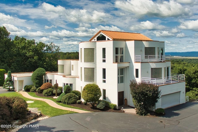 view of front facade with a garage, driveway, a balcony, and stucco siding