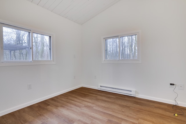 empty room with baseboards, baseboard heating, wood finished floors, and vaulted ceiling