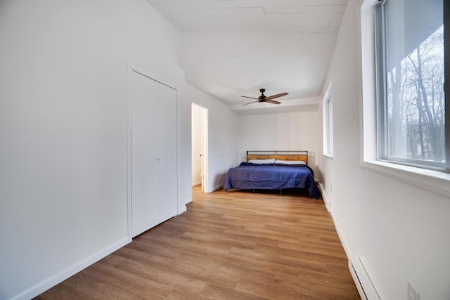 unfurnished bedroom with baseboards, a ceiling fan, vaulted ceiling, and light wood finished floors