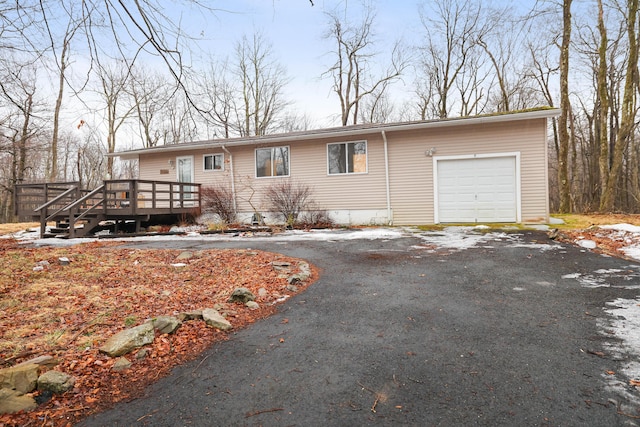 single story home with a garage, a wooden deck, and driveway