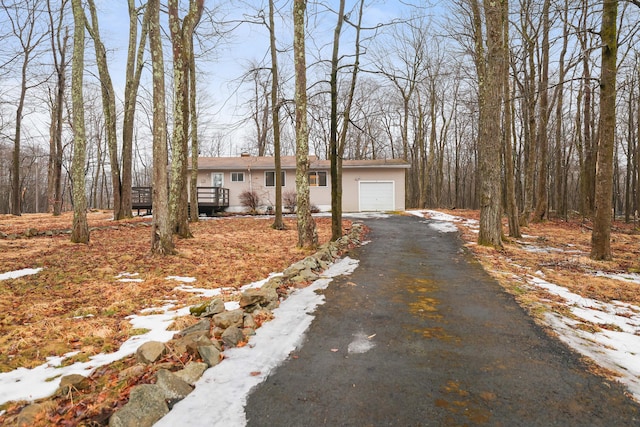 view of front of house featuring an attached garage, driveway, and a chimney