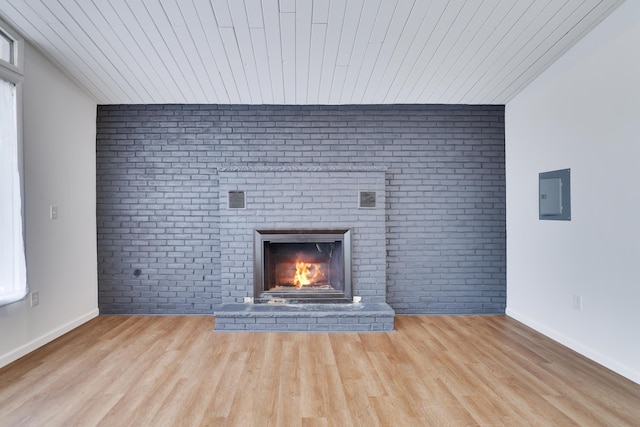 unfurnished living room featuring electric panel, a brick fireplace, wooden ceiling, and wood finished floors